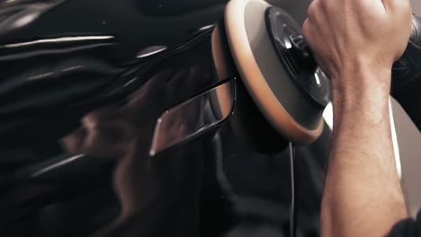 process of finishing the polishing of a new black car door.