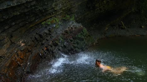 child swimming in a waterfall pool