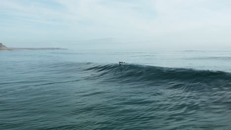 lone foil surfer being towed into a beautiful wave and surfing