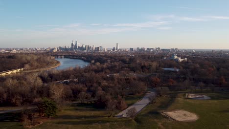 Drohnenschuss-Aus-Der-Luft,-Drohne-Fliegt-über-Einige-Baumwipfel,-Die-Sich-Rückwärts-Von-Der-Skyline-Des-Wolkenkratzers-Von-Philadelphia,-Pennsylvania,-Bewegen