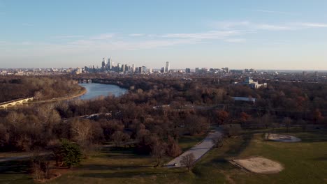 aerial dolly drone shot, drone flying over some treetops moving backward from the philadelphia skyscraper skyline, pennsylvania