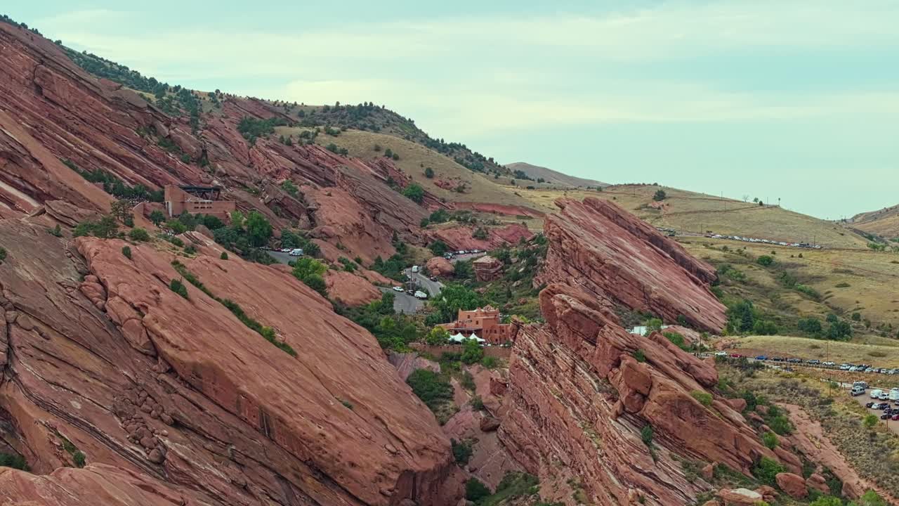 Drone pullback over Red Rocks Amphitheatre Colorado showing distinctive red cliffs and mountain backdrop