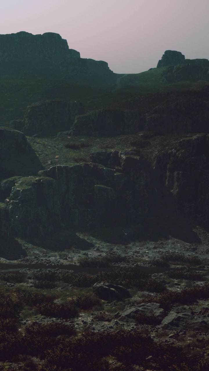 Mountain landscape with rocky terrain and distant hills during sunset