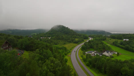 fly over highway in dense green landscape during rainy day in west coast, norway