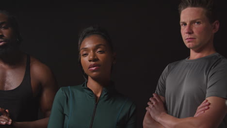 studio portrait of determined group of male and female athletes in fitness clothing training shot against black background 2