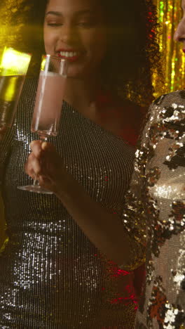 vertical video of two women in nightclub bar or disco having champagne poured from bottle