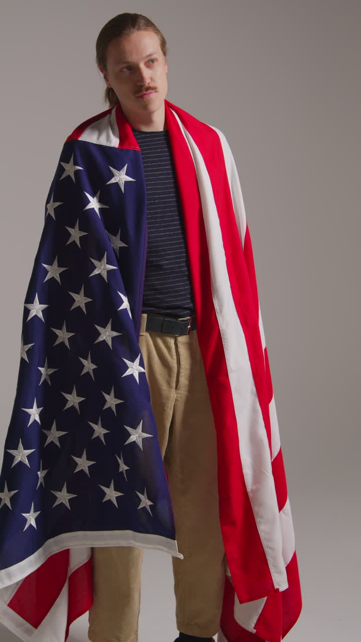 Vertical Video Studio Shot Of Man Wrapped In American Flag Celebrating 4th July Independence Day 1