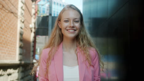 young woman smiling outdoors in a pink blazer