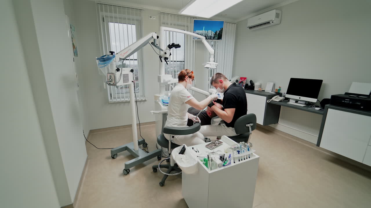 Dentists and patient in clinic. Medical treatment at dentist office