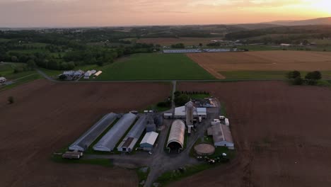 large farmstead in american city during golden sunset. aerial top down. barn, stable and livestock in rural district of pa. spring day in america.