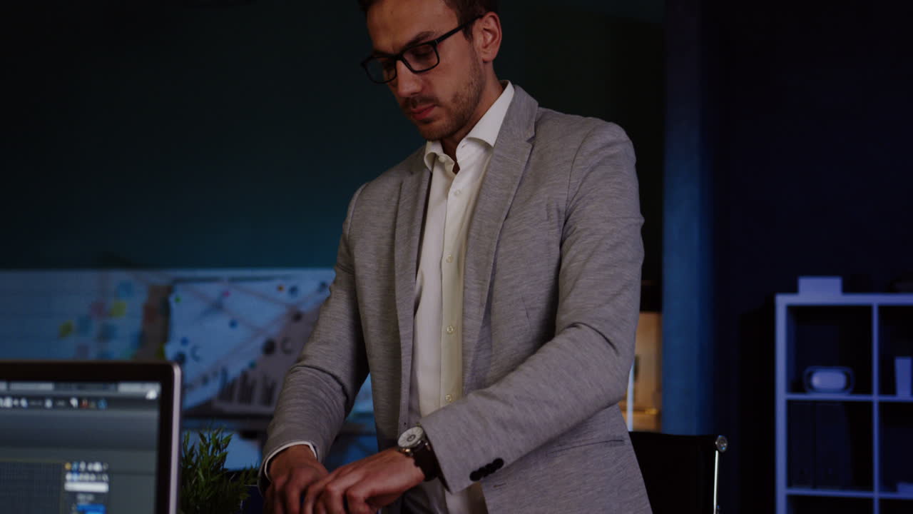 joven hombre de negocios con gafas empacando sus cosas en la oficina a altas horas de la noche