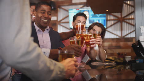 Barmaid-Serving-Group-Of-Male-Friends-On-Night-Out-For-Bachelor-Party-Making-Toast-Together