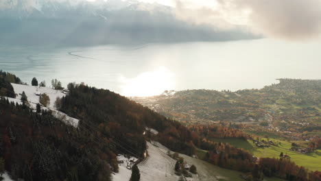 jib down of snow hillside and green calley looking over beautiful lake