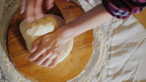 close-up - hands knead the dough on a wooden board the board is oiled with vegetable oil 4k video