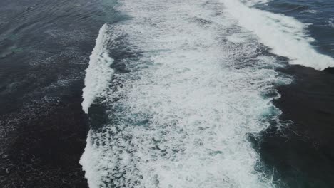 a dynamic aerial shot above large waves of water while moving its perspective upwards level to the horizon as it gradually descends