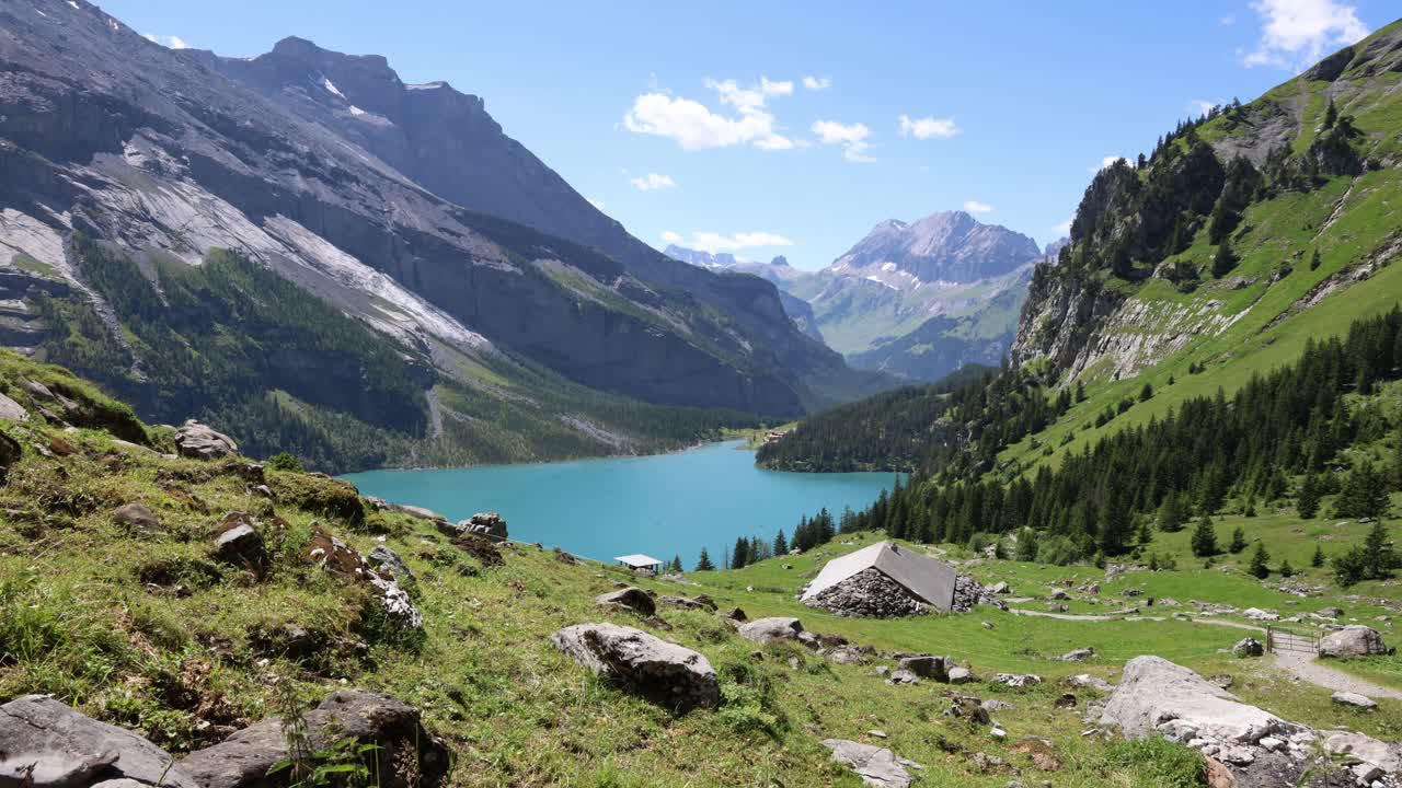 People hiking past a mountain lake in Swiss Alps, Oeschinensee timelapse