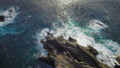 rocky ocean coast with sharp black rocks and blue water