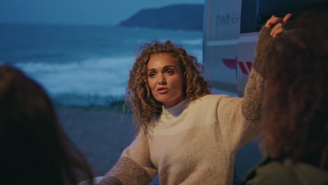 woman talking travel friends at evening ocean shore near camper van close up.