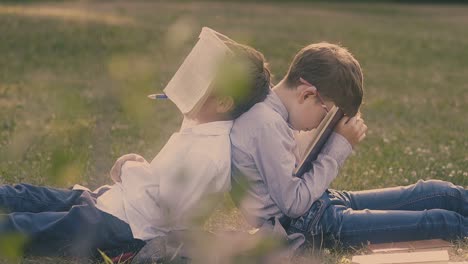 young-boy-holds-book-on-face-sitting-near-schoolmate