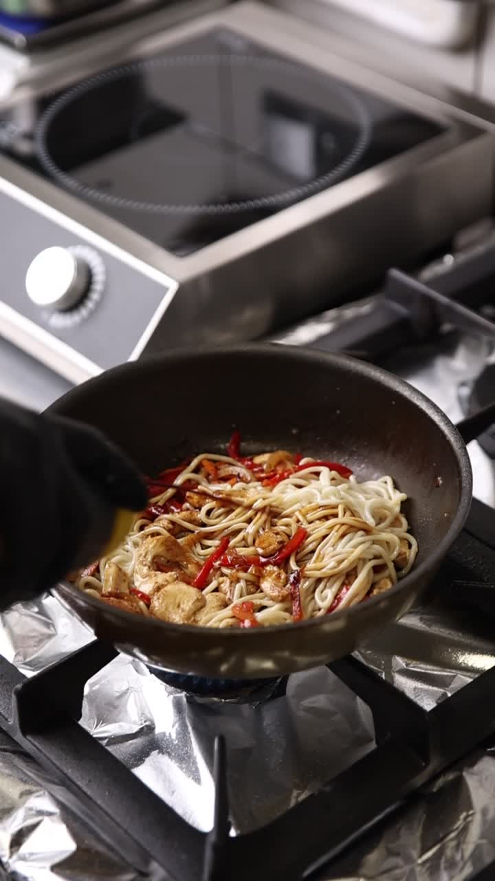 Chef che Aggiunge la Salsa a Noodles e Pollo in una Padella Calda
