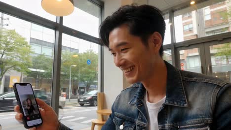 happy asian man on a video call in a modern cafe