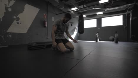 young athletic man doing push ups at the gym, resting in between series