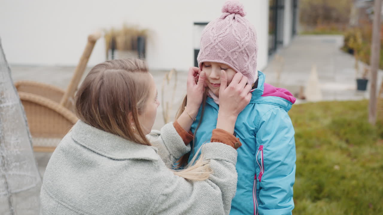 어머니는 딸이 정원에서 옷을 입는 데 도움을 줍니다.