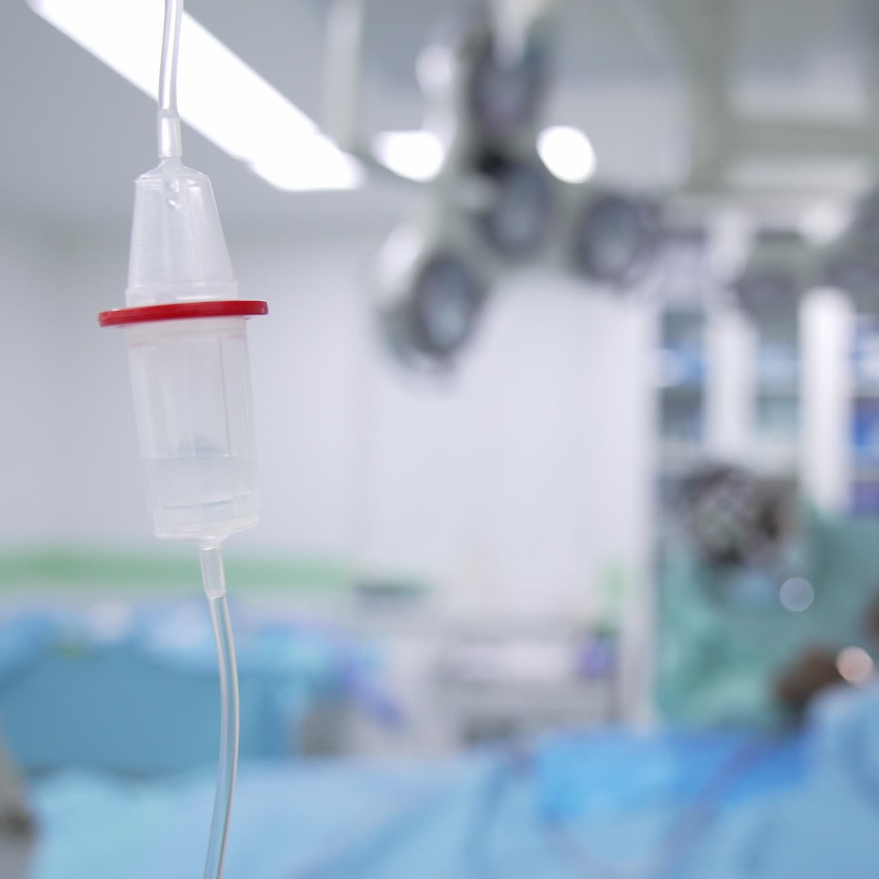 Medicinali che gocciolano lentamente all'interno del serbatoio del conta gocce. Chirurghi che eseguono un'operazione sullo sfondo in modalità sfocata