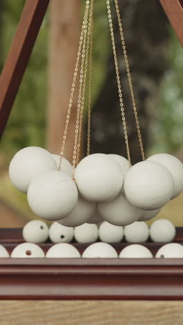 board game with wooden playing field and suspended white balls. spending leisure time in yard on sunny day. suspense badaboum on blurred background