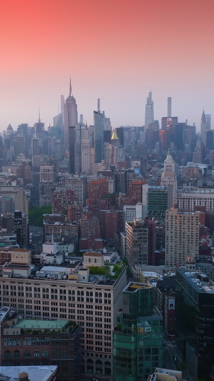 Peaceful and satisfying New York panorama in the rays of setting sun. Stunning pink and orange skies over the gorgeous city. Top view. Vertical video
