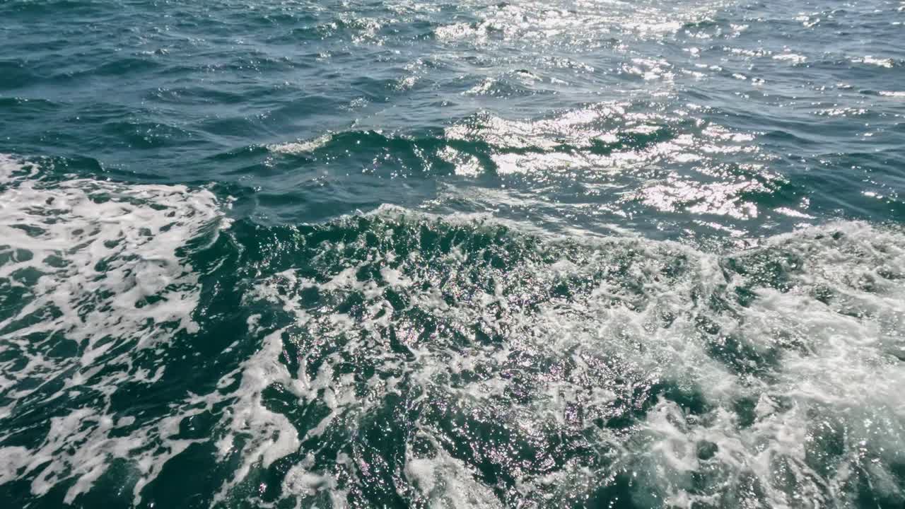 Ondas oceânicas dinâmicas e reflexos do sol capturados atrás de um barco de pesca em movimento perto da Praia de Rawai, Phuket, Tailândia