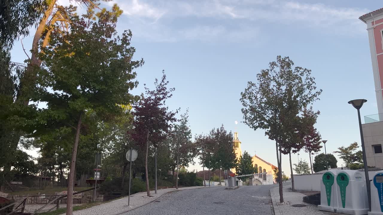 crepúsculo en una calle de lisboa con árboles y una iglesia lejana en un día soleado, lisboa, portugal