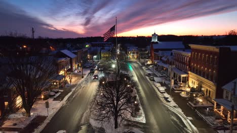 american flag waving in snowy small town square during sunset