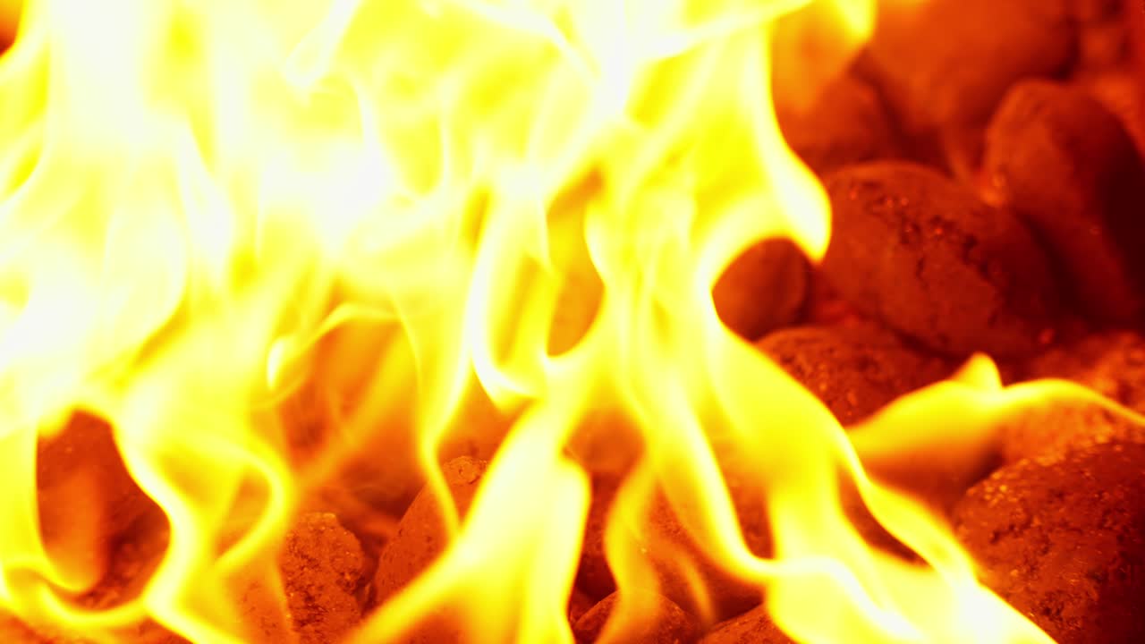 Close-Up of Fiery flames burning coal briquettes preparing BBQ grill