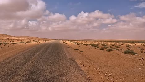 first-person pov driving along solitary tunisia desert road, car driver point of view