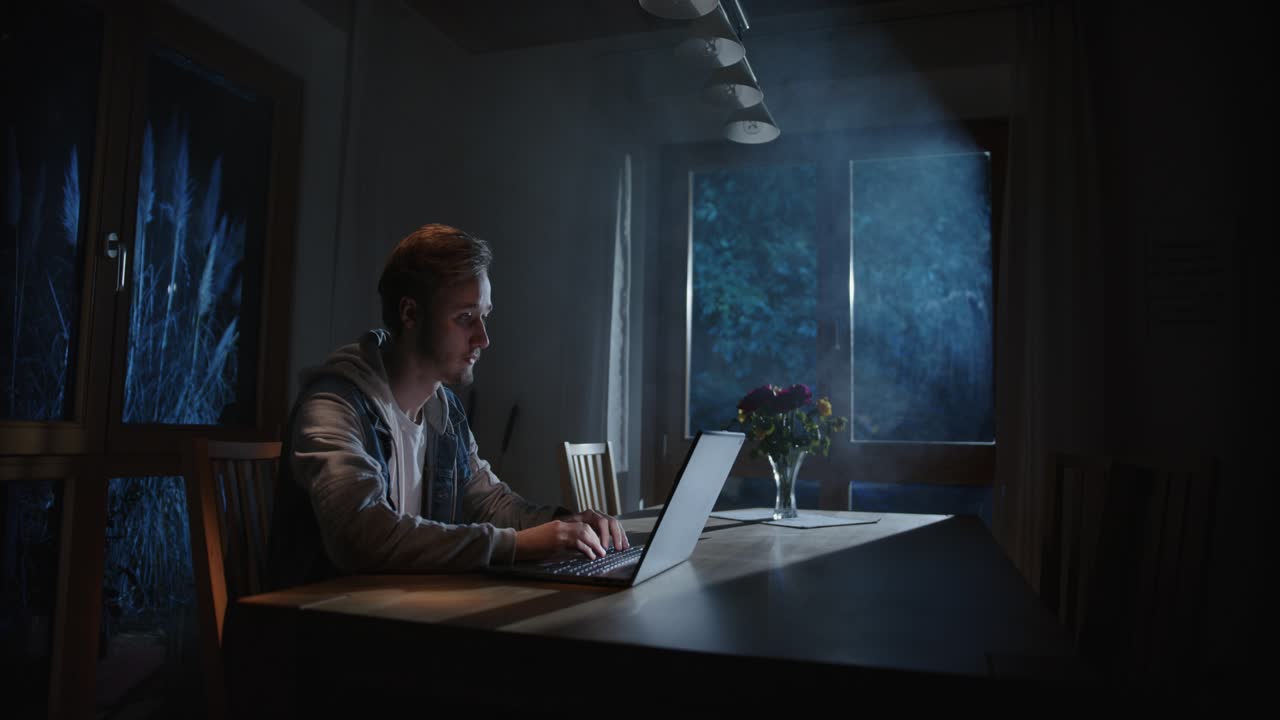 qualcuno sta digitando sul portatile in soggiorno di notte, con la luce proveniente dall'esterno