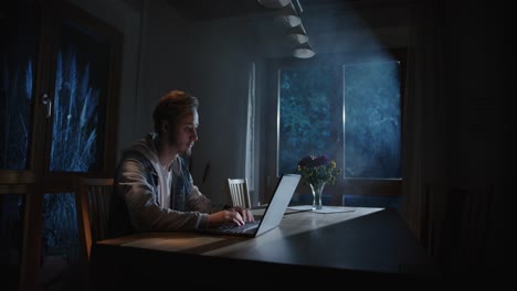 alguien está escribiendo en la computadora portátil en la sala de estar por la noche, con luz del exterior