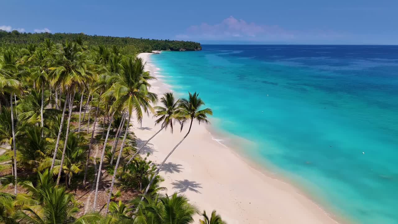 Video drone 4K Pantai Mandel, sebuah pantai pasir putih yang indah di Kepulauan Banggai di Sulawesi, Indonesia. Terlihat samudra biru cerah dengan ombak yang bergulir ke tepi pantai pasir putih