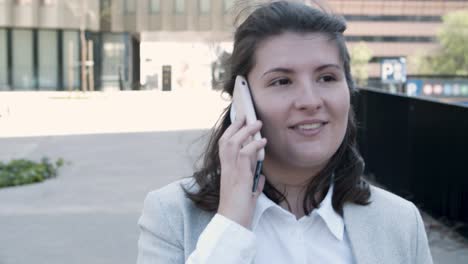 un joven gerente sonriente hablando en un teléfono inteligente durante un paseo