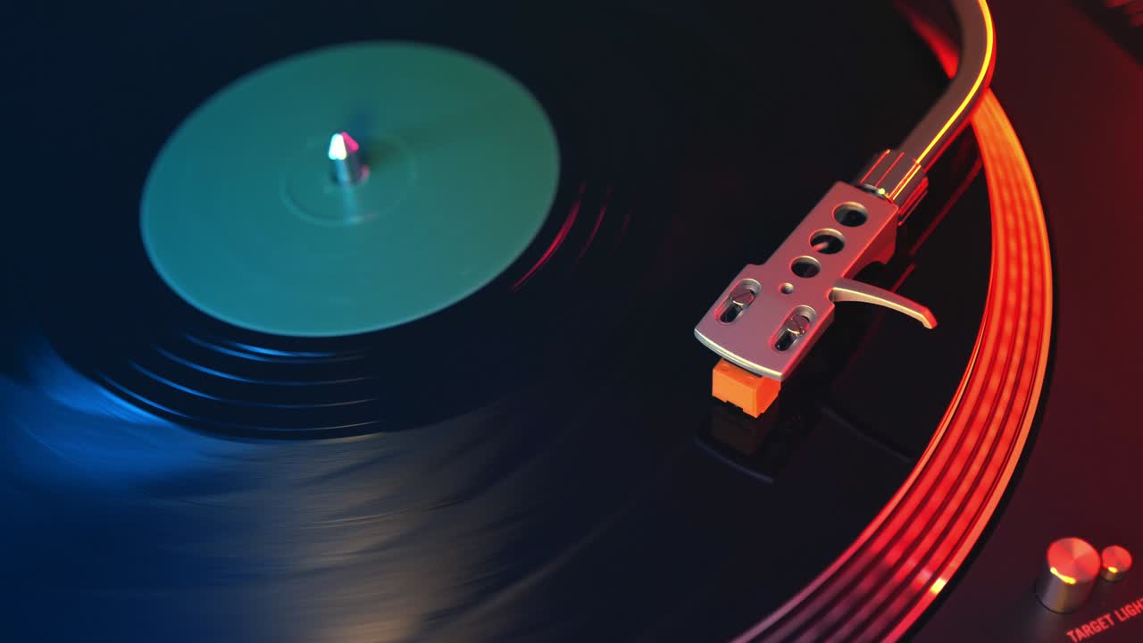 초점을 맞추지 않는 플레이어 비닐 레코드 턴테이블 빨간색과 파란색 불빛의 배경에서 근접. 바늘은 회전하는 검은 비닐 레코드에서 부드럽게 슬라이드