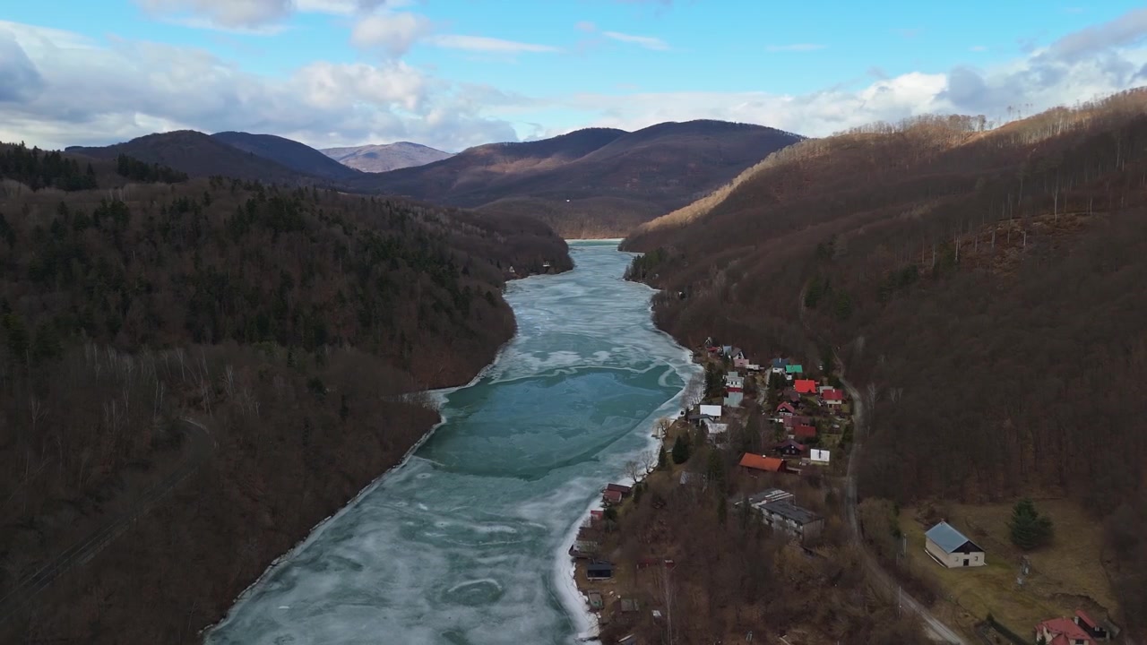 Nella regione di Košice, Slovacchia orientale, il bacino ghiacciato di Ružín si trova in una valle di montagna vicino a Malý Folkmar, con boschi spogli e cottage sparsi visibili in una vista aerea.