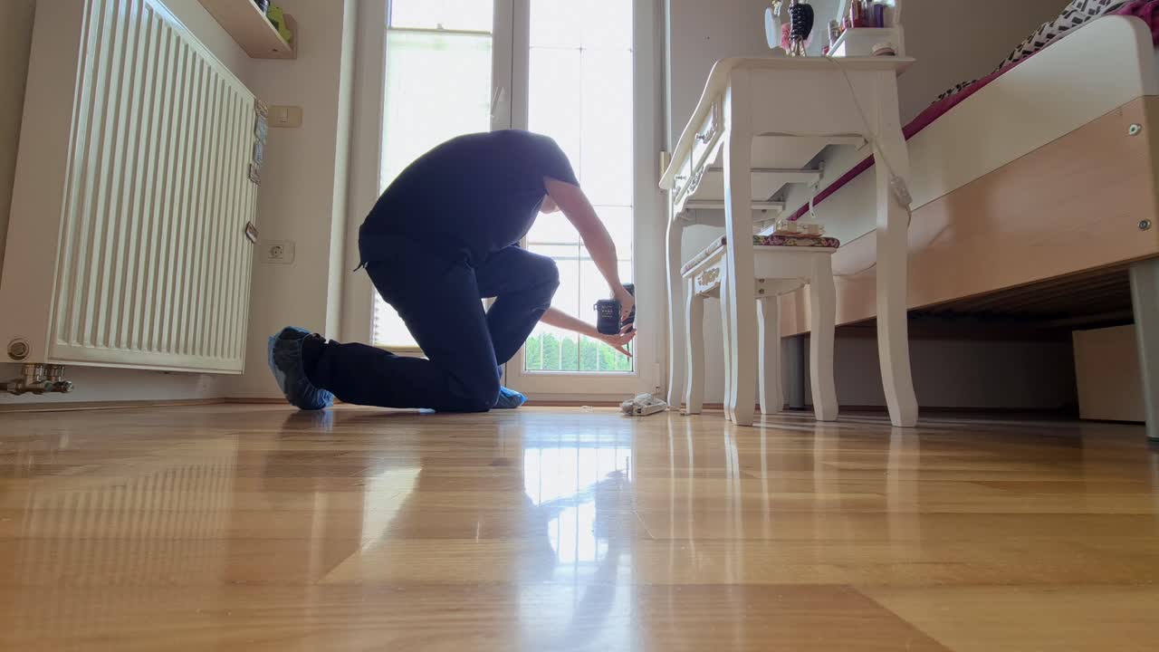 Manlig husägare installerar fönsterskydd inomhus.