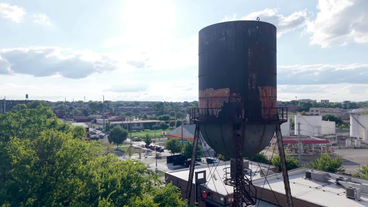 Old and rusted water tower tank - ascending aerial reveal on a sunny day
