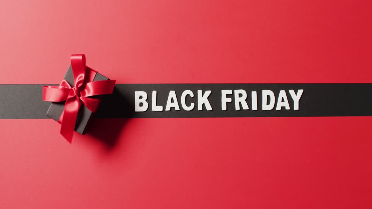 текст черной пятницы белым цветом на черной полосе и черной подарочной коробке с красной лентой на красном фоне