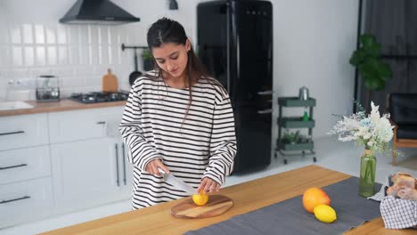 mujer cortando frutas cítricas en una cocina moderna