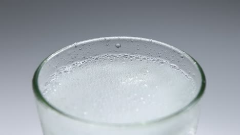 pouring-sparkling-soda-water-into-glass-with-ice-cubes