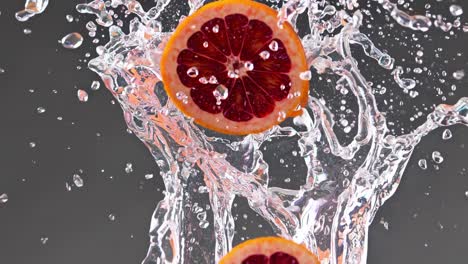 two slices of blood orange making a big splash in crystal clear water with drops and bubbles flying all around on a dark gray background, creating a refreshing and dynamic image