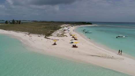 drone shot couple walking barefoot on white sand beach, stunning island cayo de agua