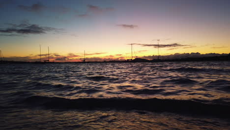 Peaceful-scenery-of-calm-waves-during-colorful-sunset-in-Auckland,-slow-motion