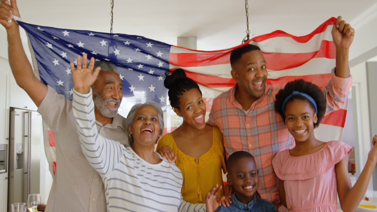 Front view of multi-generation black family holding american flag in a comfortable home 4k